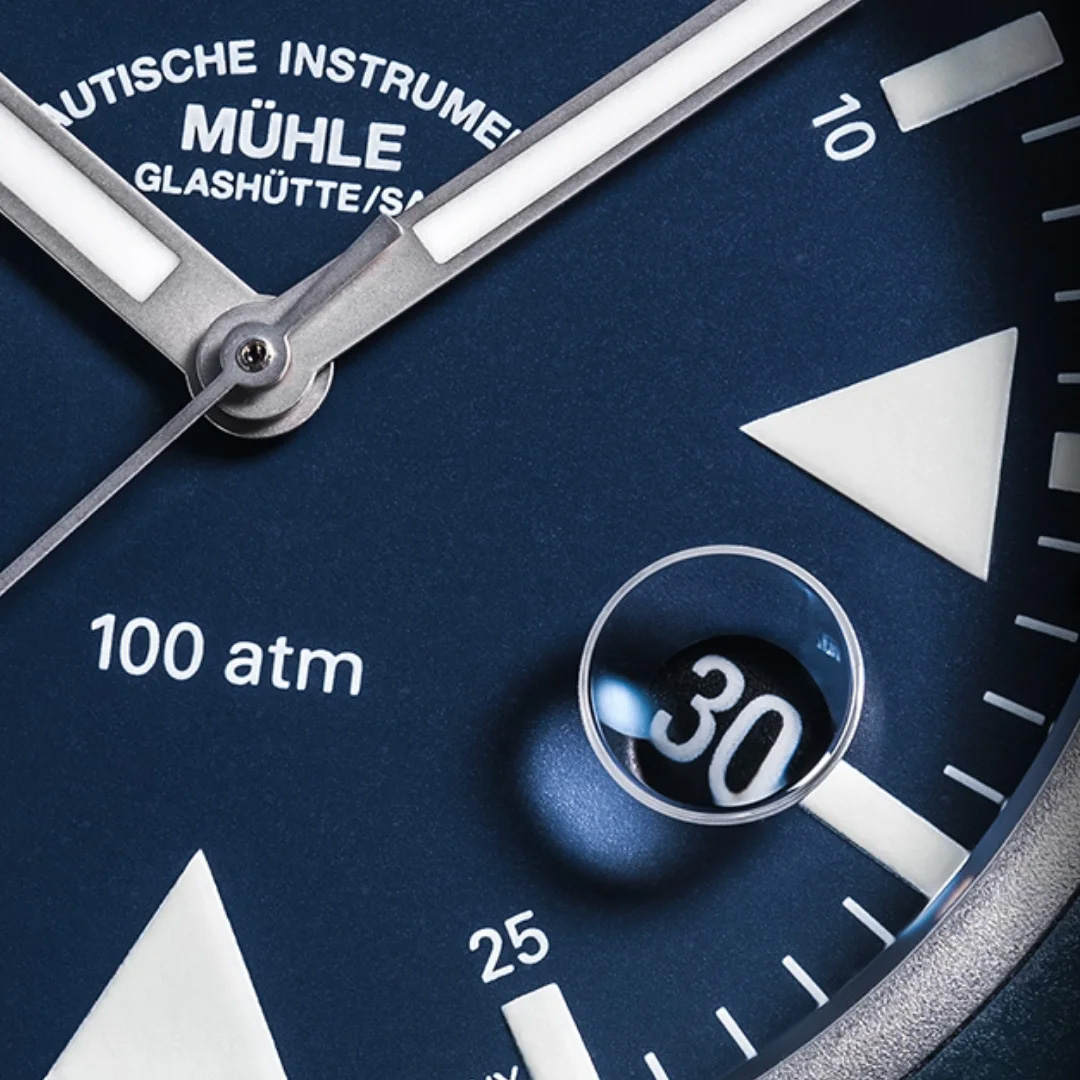 Nahaufnahme der ins Saphirglas eingelassenen Lupe und Super-LumiNova-Index auf Nautikblau.
